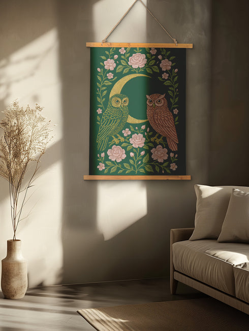 26x36 inch vertical wall tapestry printed on silky polyester, featuring a pair of embroidered-style owls perched on a golden crescent moon, surrounded by pink vintage-style florals and greenery on a forest green background. Includes stained wood slats and twine for easy hanging. A romantic, nature-inspired design for woodland and cottagecore decor lovers.